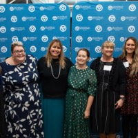 Group of women pose in front of GVSU backdrop